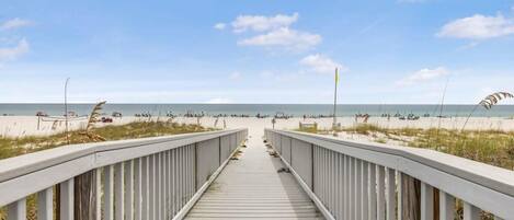 A wooden boardwalk leading to a beach with a clear sky.