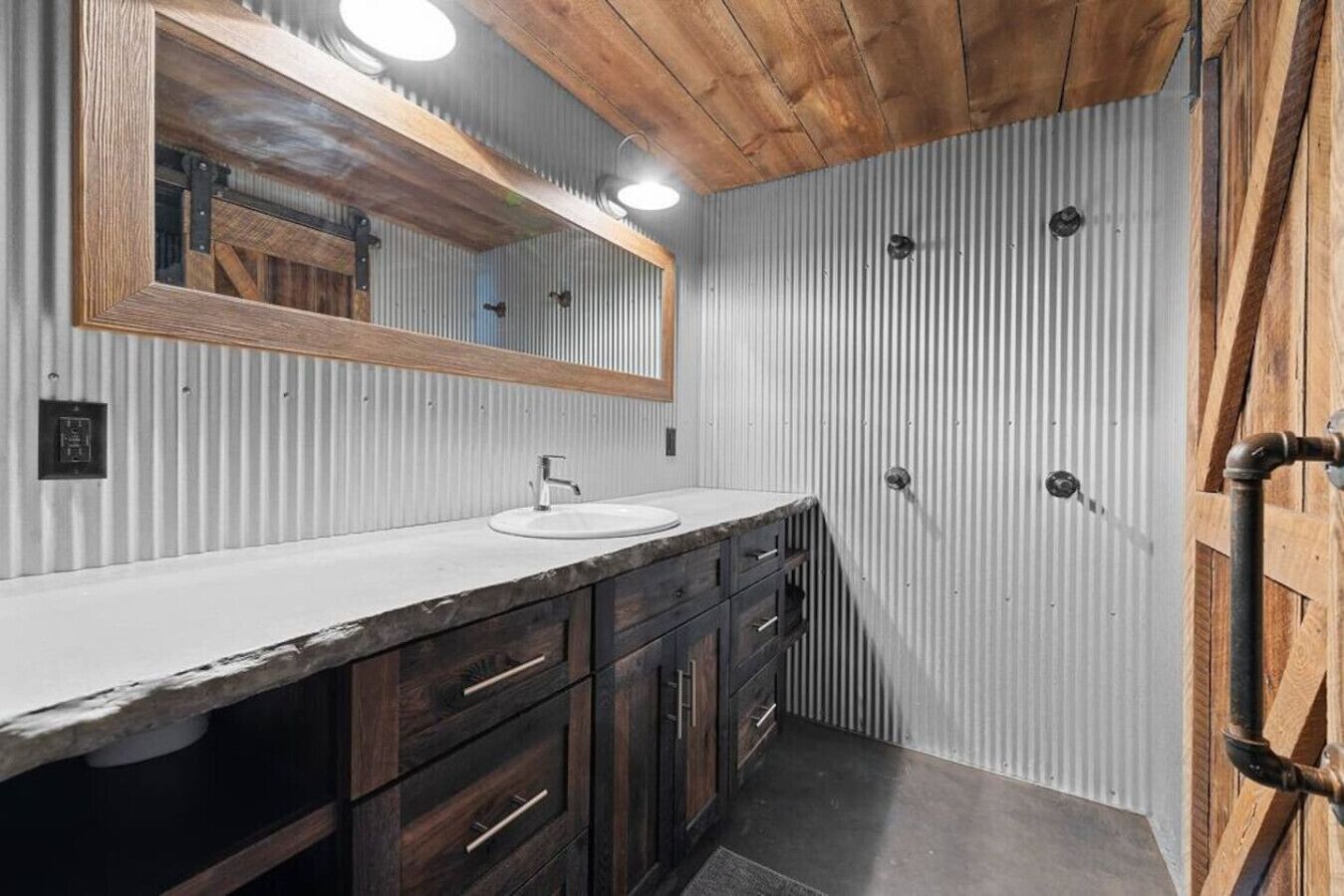 Un baño con tocador de madera, lavamanos blanco y espejo.