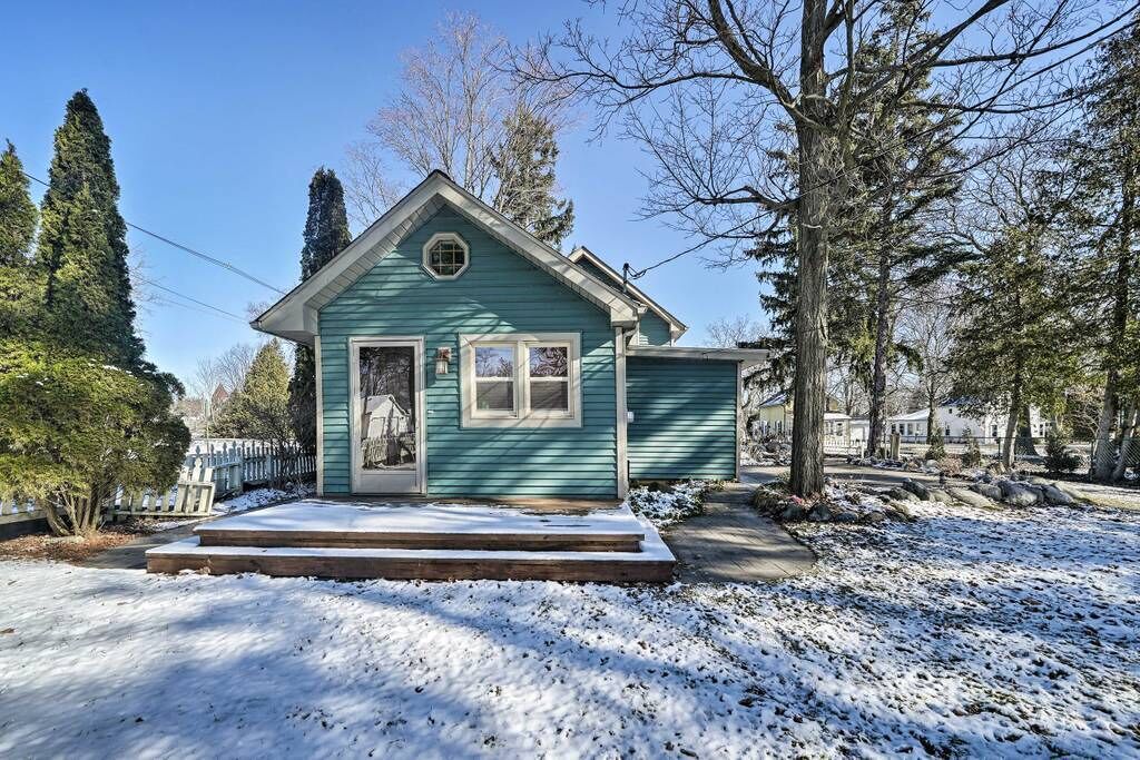 Ein kleines, eingeschossiges Haus mit einer Veranda und einem überdachten Eingang, umgeben von Schnee und Bäumen.