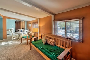 Una habitación acogedora con un banco de madera, un cojín verde y una ventana con persianas.