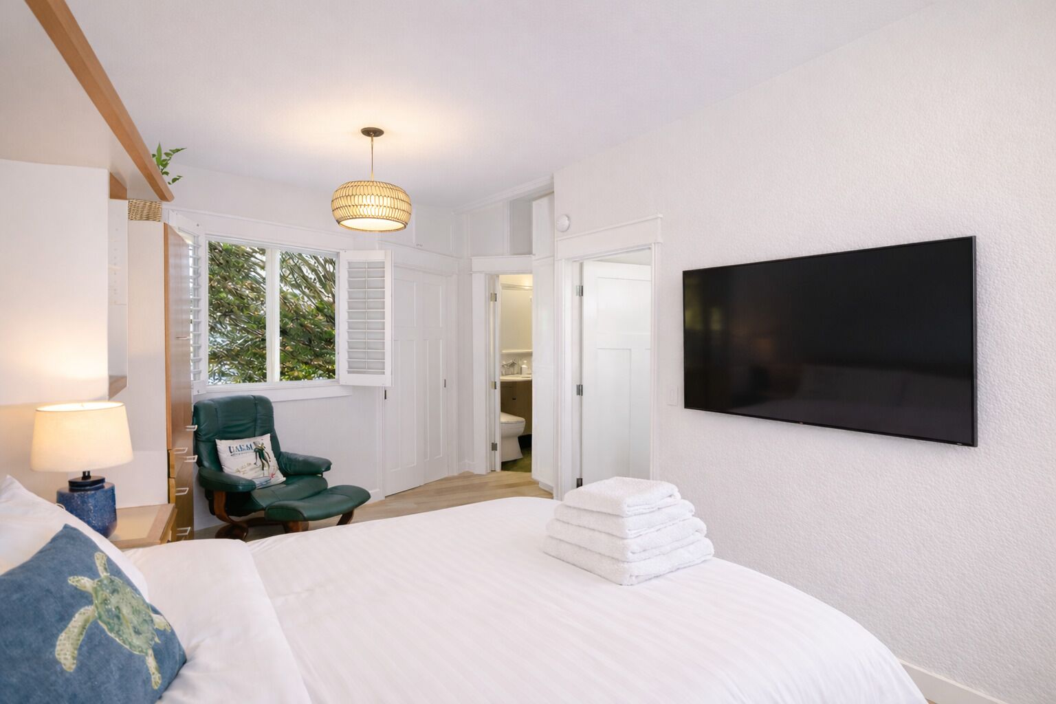 Een slaapkamer met een bed, een stoel, een televisie en een raam.