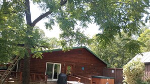 Une cabane en bois dotée d’un patio, d’une table de pique-nique et de mobilier d’extérieur.