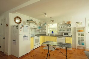 Une cuisine avec des meubles blancs, un four à micro-ondes, une cuisinière et une table à manger.