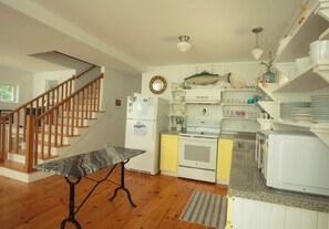 Une cuisine avec un plancher en bois, une table en marbre, un élément décoratif représentant un poisson et un escalier.
