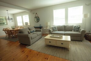 A living room with a sofa, a coffee table, and a dining area with chairs and a table. - Your Kennebunkport Home Base (Kennebunkport)