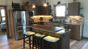 A modern kitchen with wooden cabinets, stainless steel appliances, and a central island with bar stools. - Your Basecamp In the Tetons.  (Victor)