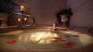 Een vrouw ontspant in een jacuzzi, met rozenblaadjes die in het water drijven.