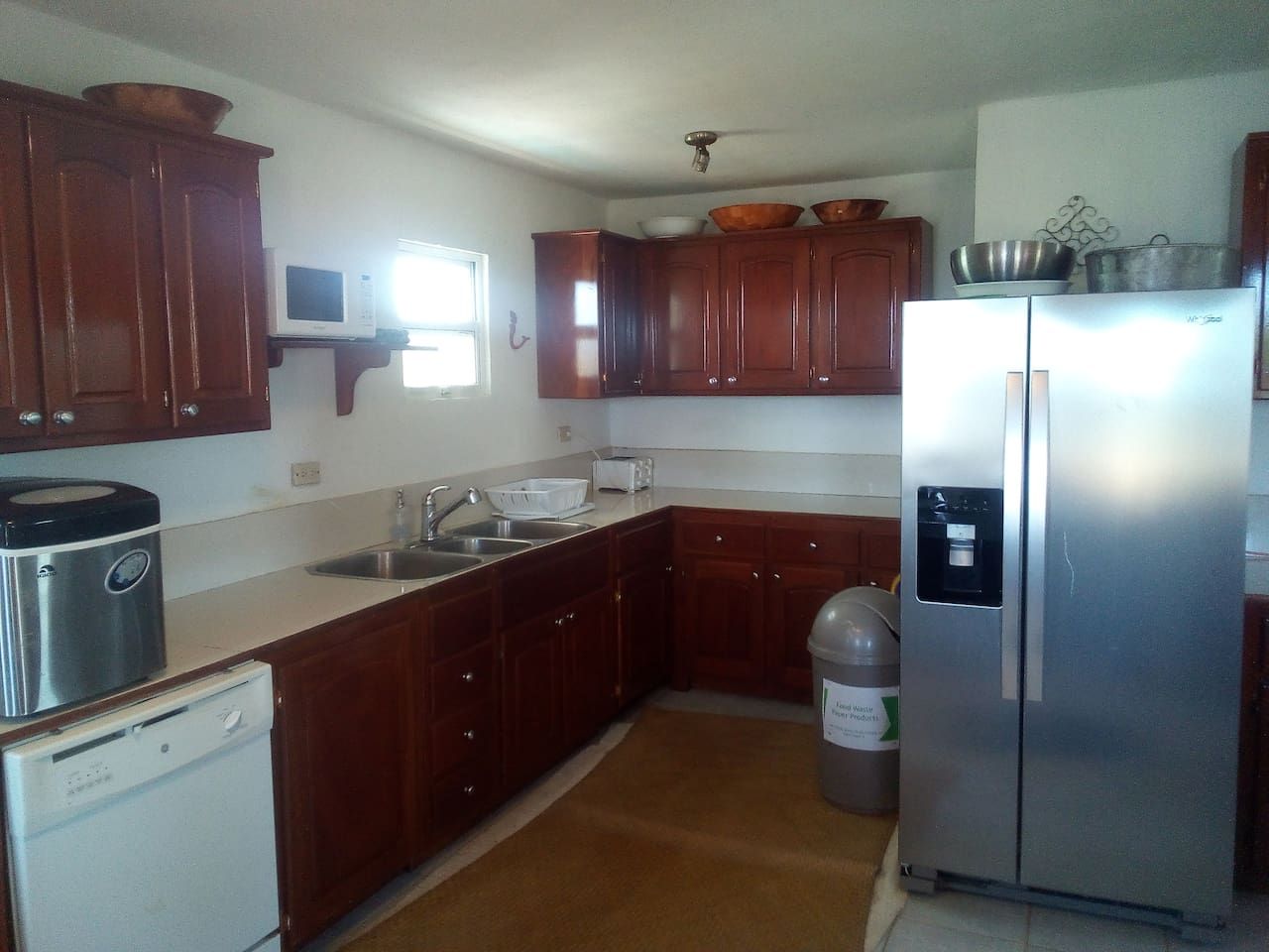 A kitchen with wooden cabinets, a stainless steel refrigerator, a microwave, and a dishwasher.