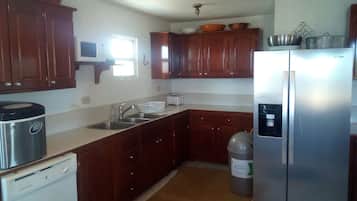 A kitchen with wooden cabinets, a stainless steel refrigerator, a microwave, and a dishwasher.