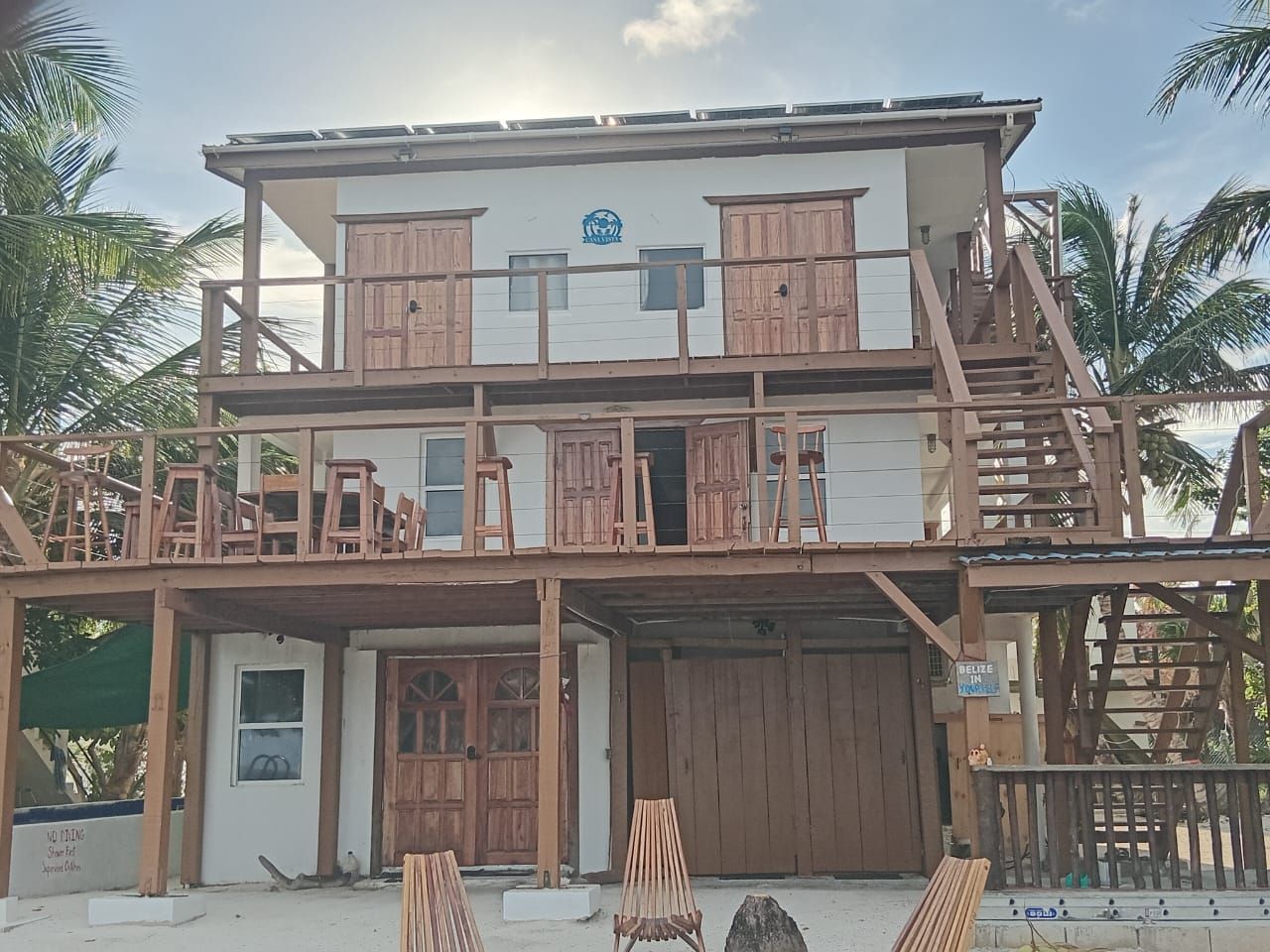 A two-story building with a wooden facade, multiple balconies, and a sign indicating Belize.