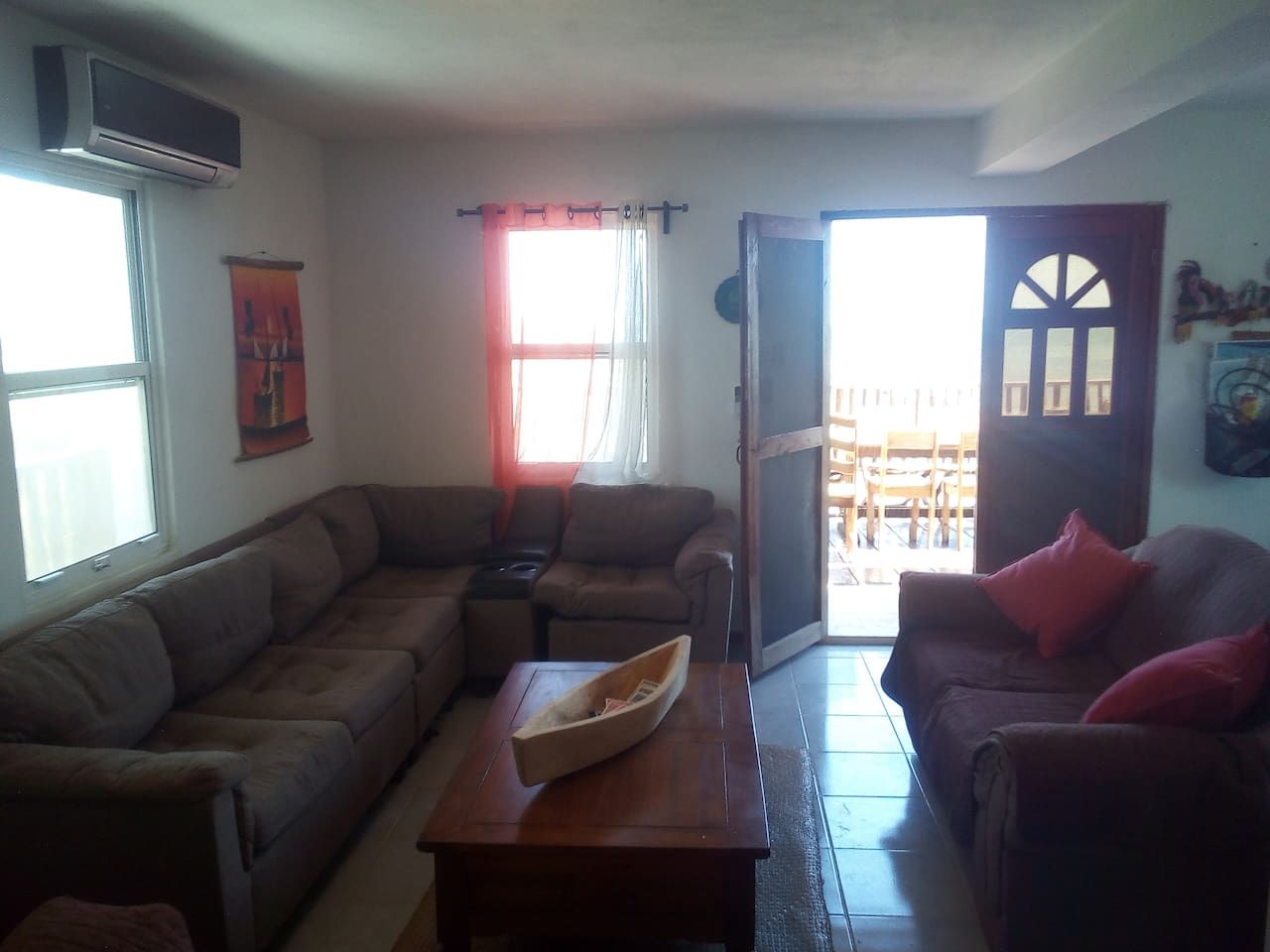 A living room with a sectional sofa, a coffee table, and a door leading to an outdoor area.