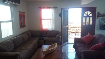 A living room with a sectional sofa, a coffee table, and a door leading to an outdoor area.
