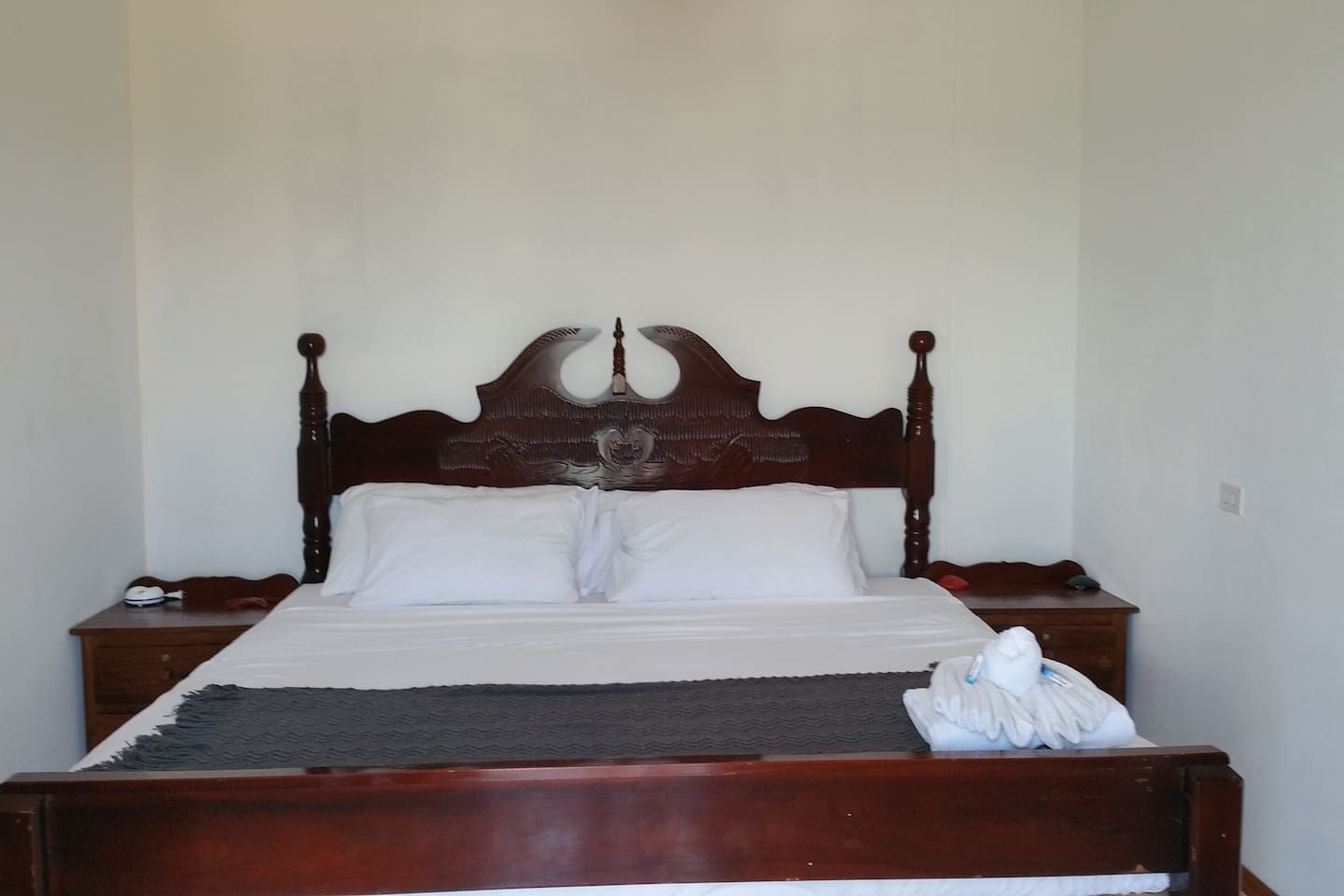 A standard single bed with a wooden headboard and two bedside tables.