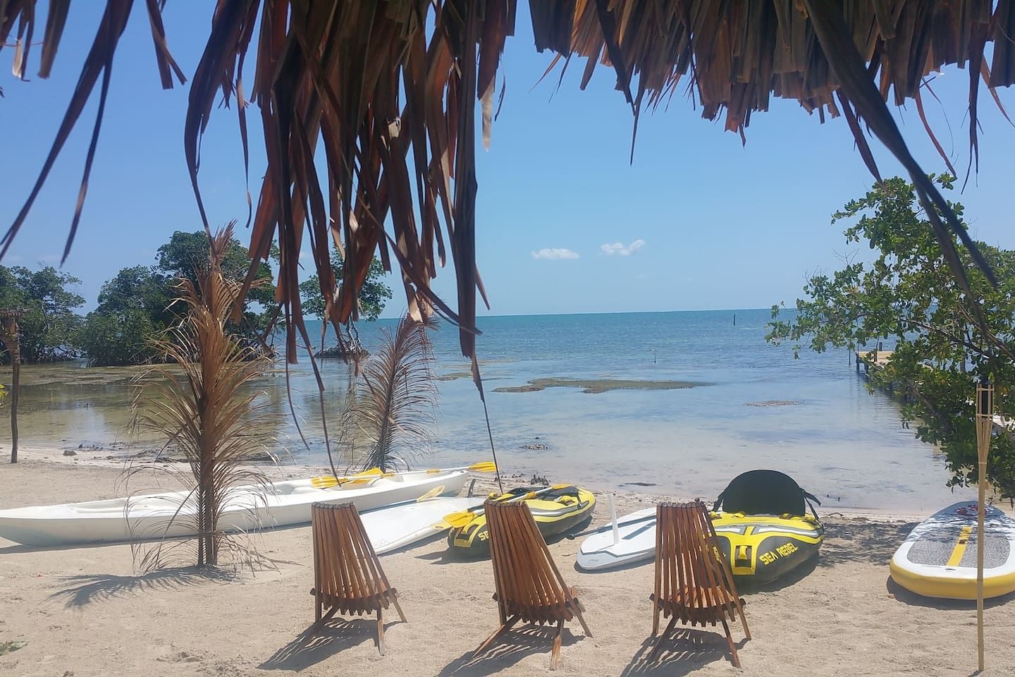 Une plage offrant une vue dégagée sur l’océan, avec quelques bateaux et des chaises longues.