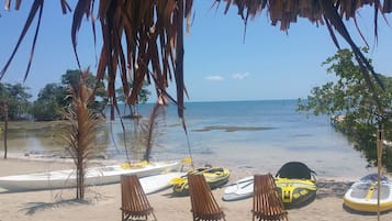 A beach with a clear view of the ocean, a few boats, and lounge chairs.
