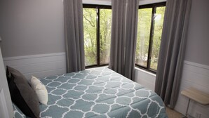 Ein Schlafzimmer mit einem Bett, einem Fenster und einem Nachttisch.