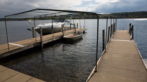 Ein Steg mit einem überdachten Boot und einem kleinen Ruderboot.