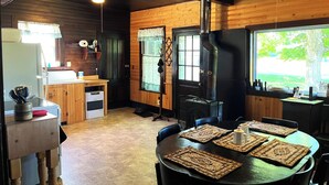 Een rustiek blokhutinterieur met een keuken, eethoek en een houtkachel.