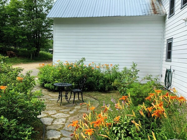 A white house with a stone pathway leading to a small patio with a table and chairs. - Peaceful ADK Escape - Whiteface Mtn & Lake Placid (Bloomingdale)