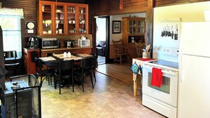 Een keuken met houten kastjes, een eettafel, stoelen, een fornuis en een koelkast.