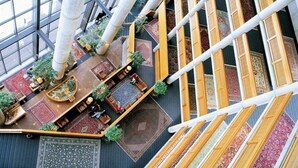 Un atrium intérieur doté d’un haut plafond, de grandes fenêtres et d’un espace de détente central avec des canapés et des tapis.