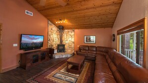 Ein gemütliches Wohnzimmer mit Kamin aus Stein, einer Ledersofa und einem Flachbildfernseher.