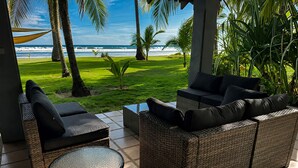 An outdoor seating area with wicker furniture, a round table, and a view of the ocean.