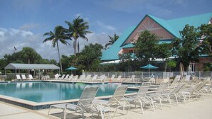 Une piscine avec des chaises longues et un bâtiment doté d’un toit végétalisé.