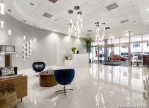 Un vestíbulo moderno con una recepción, zona de estar y entrada de vidrio.