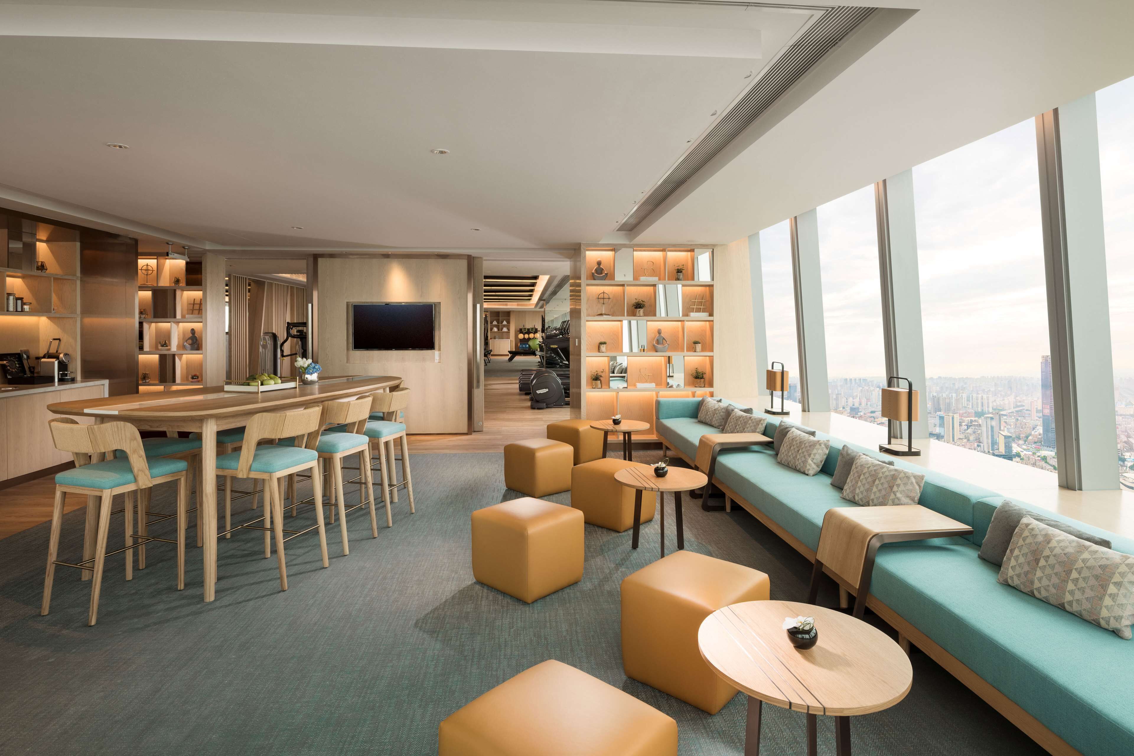 A modern hotel lobby with a bar, seating area, and large windows offering a city view.