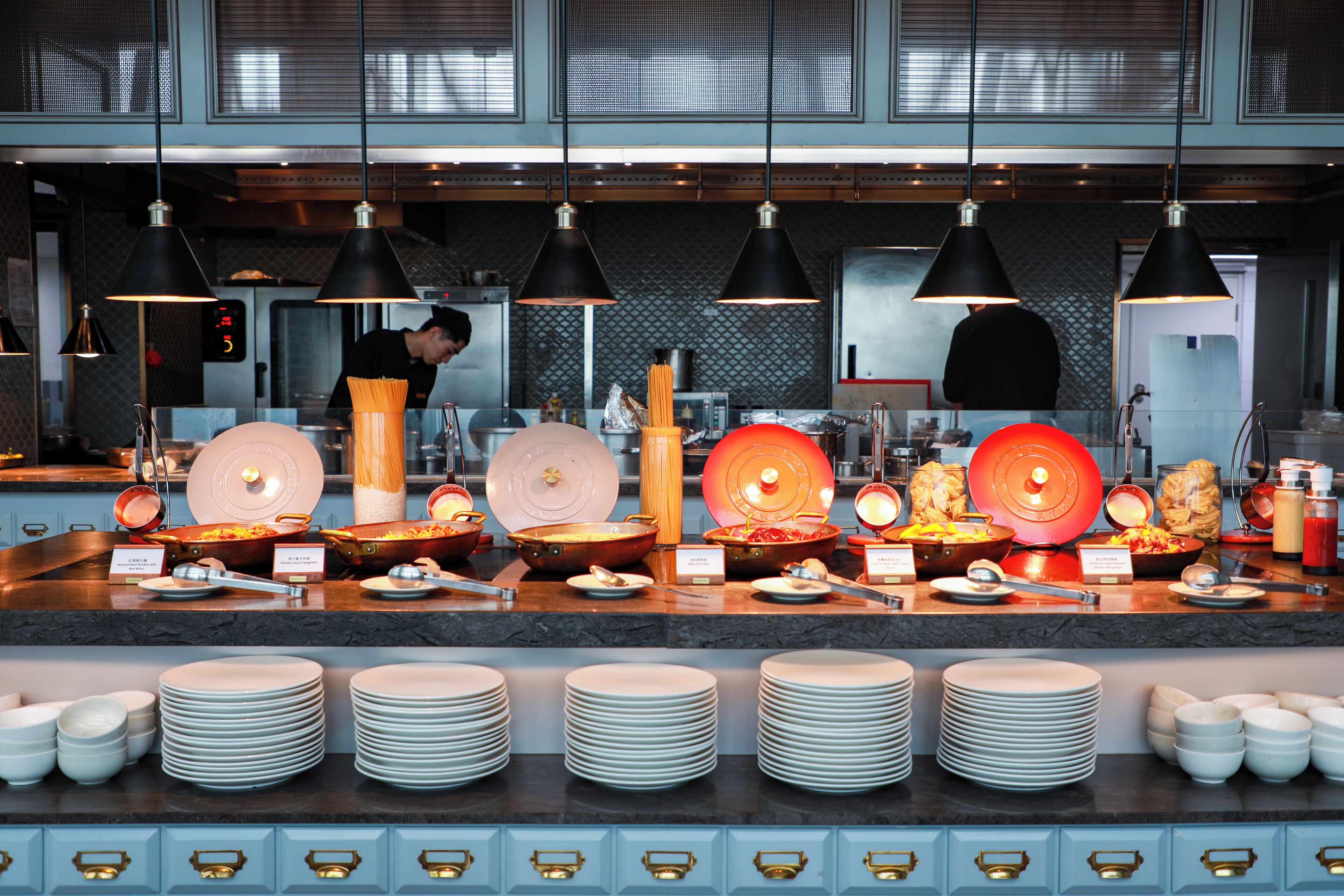 A buffet setup with multiple food stations and a chef preparing food in the background.