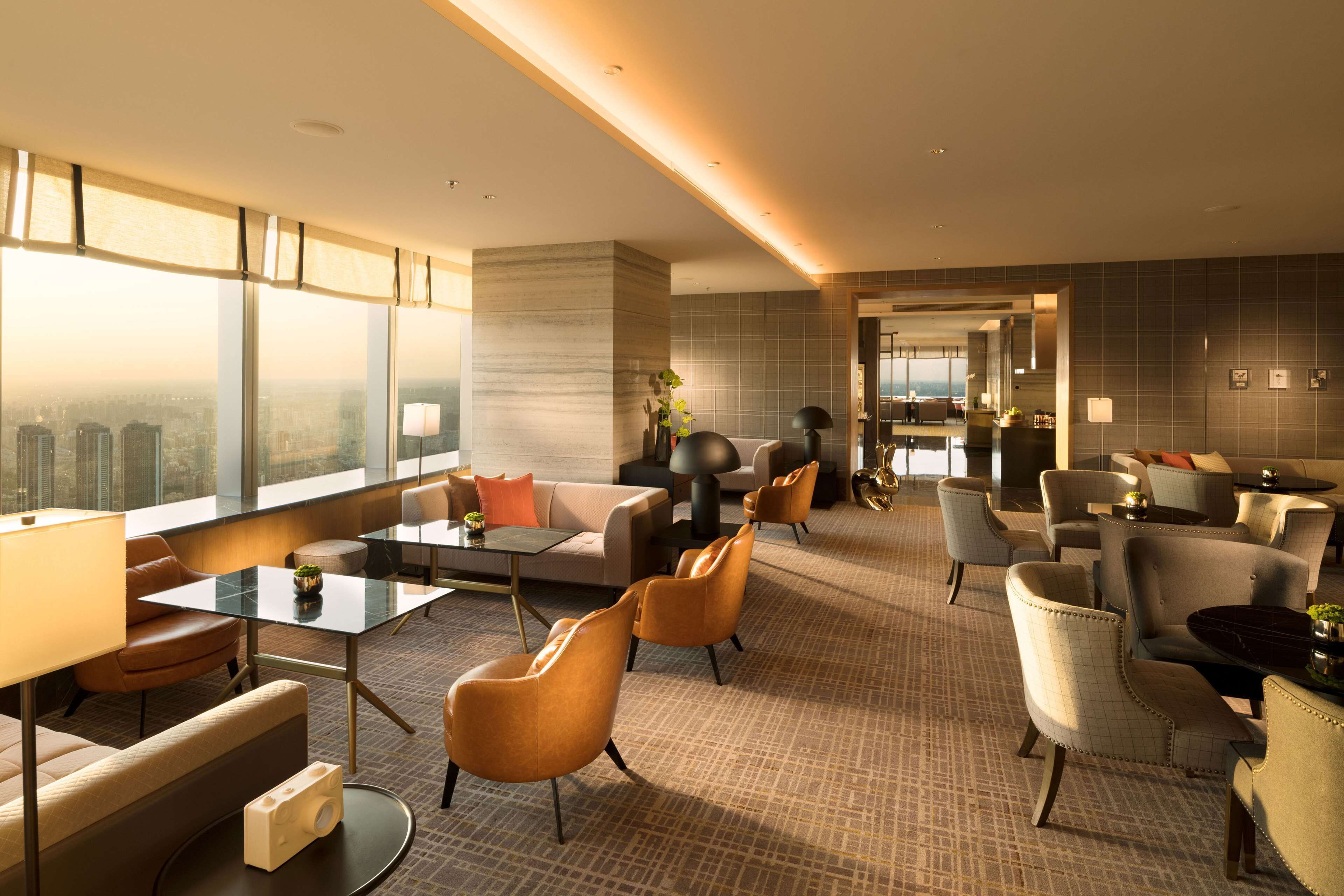 A modern hotel lobby with a seating area, a coffee table, and a view of the city.