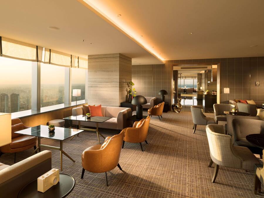 A modern hotel lobby with a seating area, a coffee table, and a view of the city.