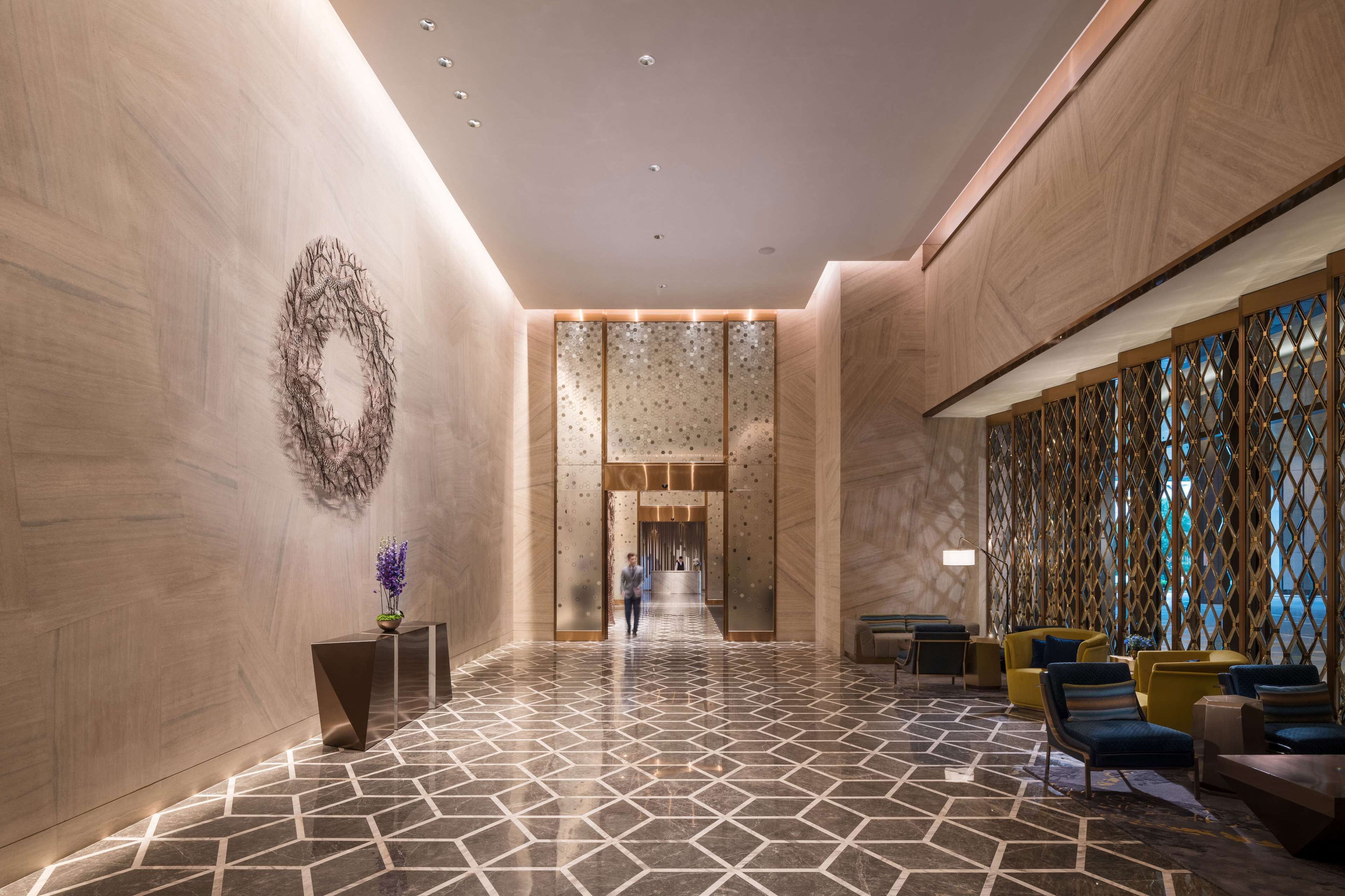 A modern lobby with a geometric tile floor, a reception desk, and seating areas.