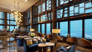 A spacious lobby with a high ceiling, large windows, and modern furnishings including sofas, chairs, and tables. - Conrad Shenyang (Shenyang)