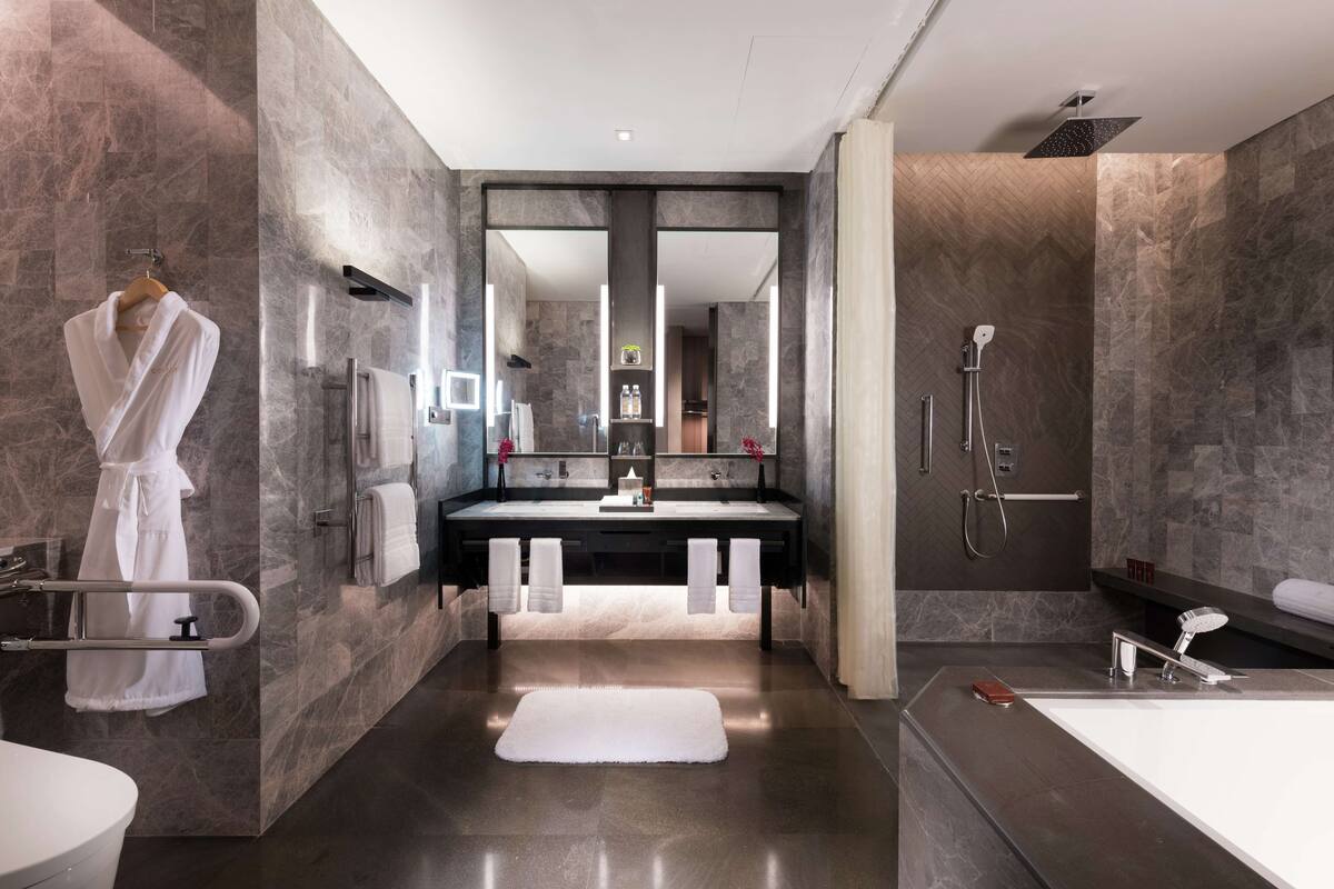 A modern bathroom with a large mirror, a bathtub, and a shower area.