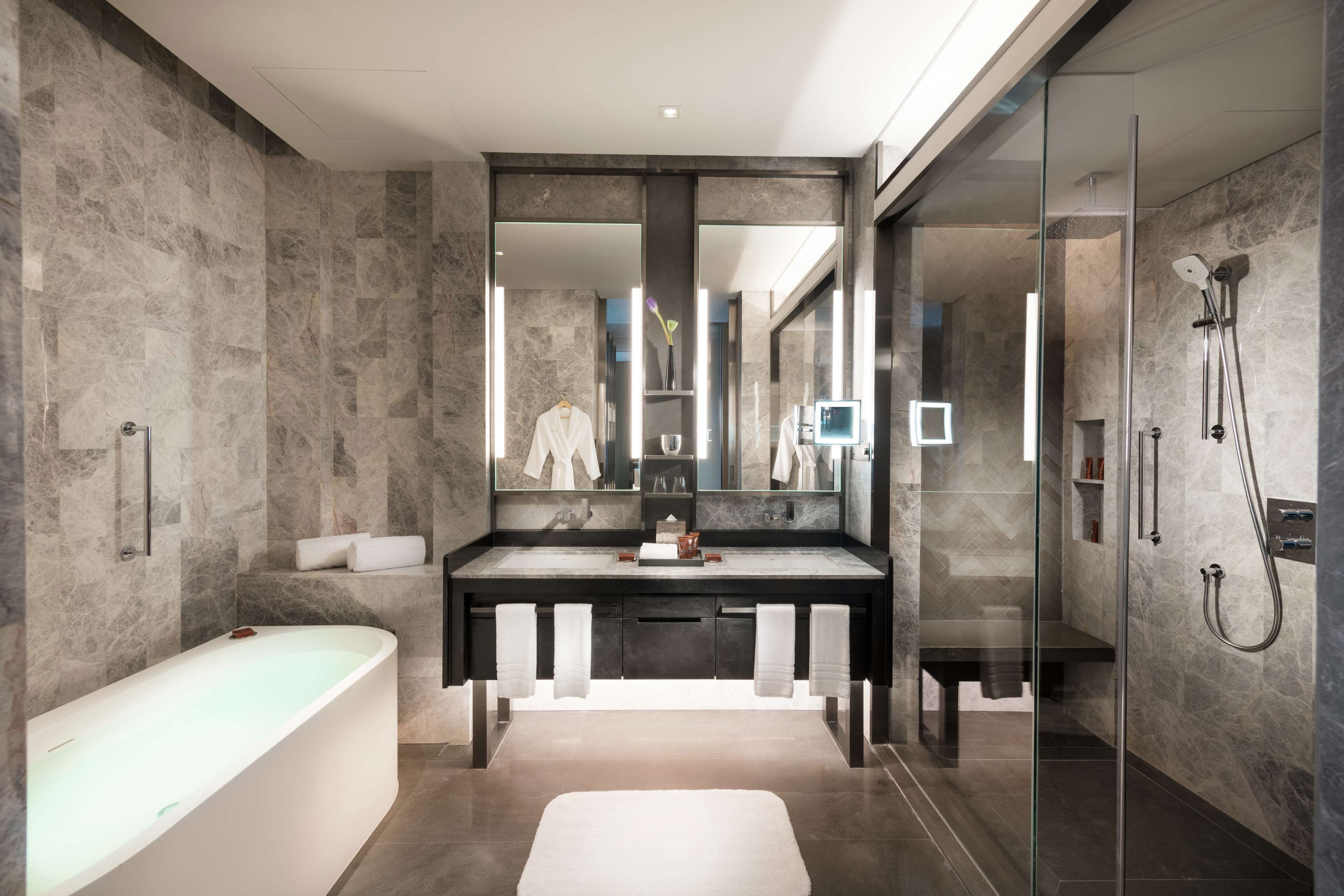 A modern bathroom with a freestanding bathtub, a large mirror, and a glass-enclosed shower area.