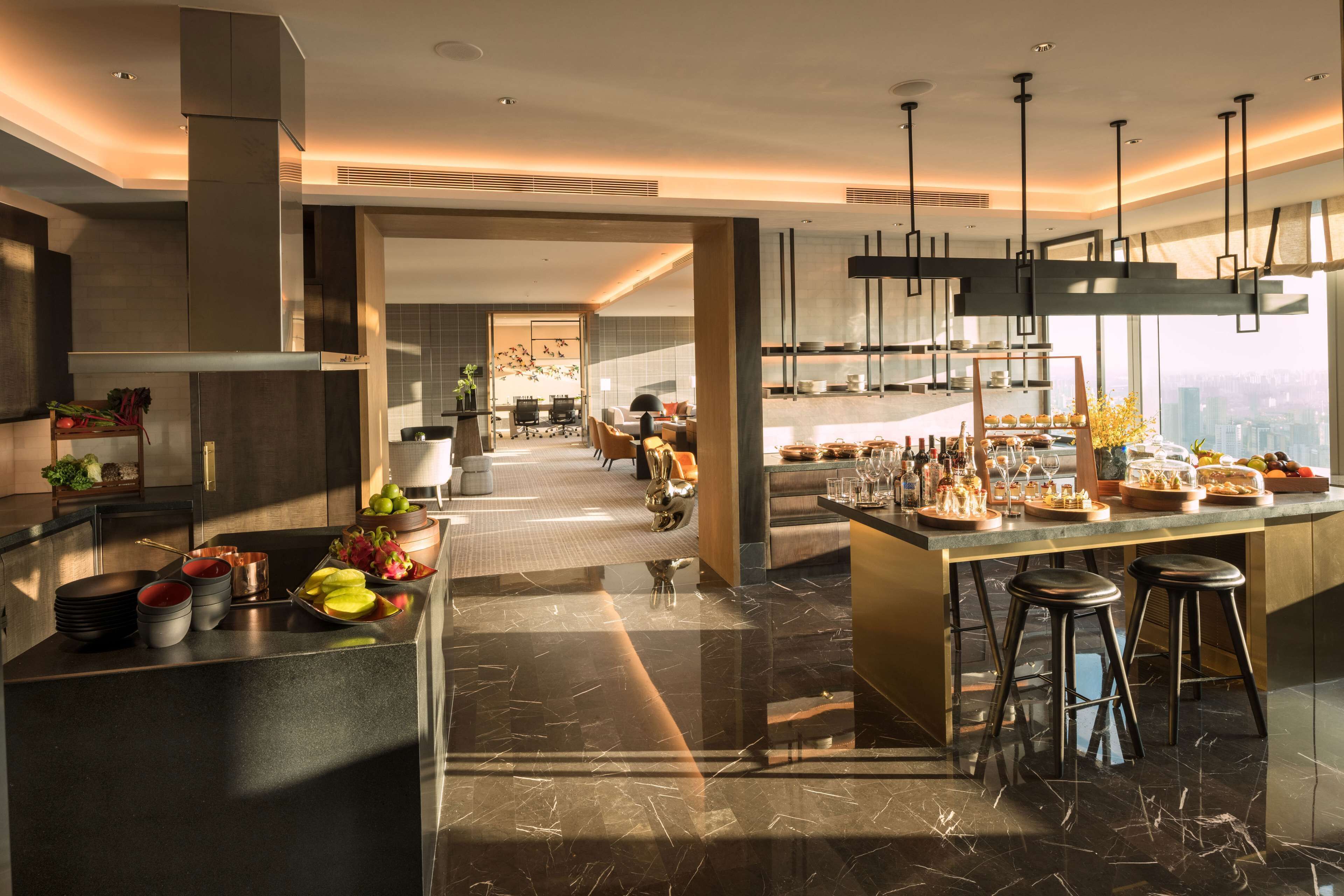 A modern kitchen with a central island, bar stools, and a view of the city.