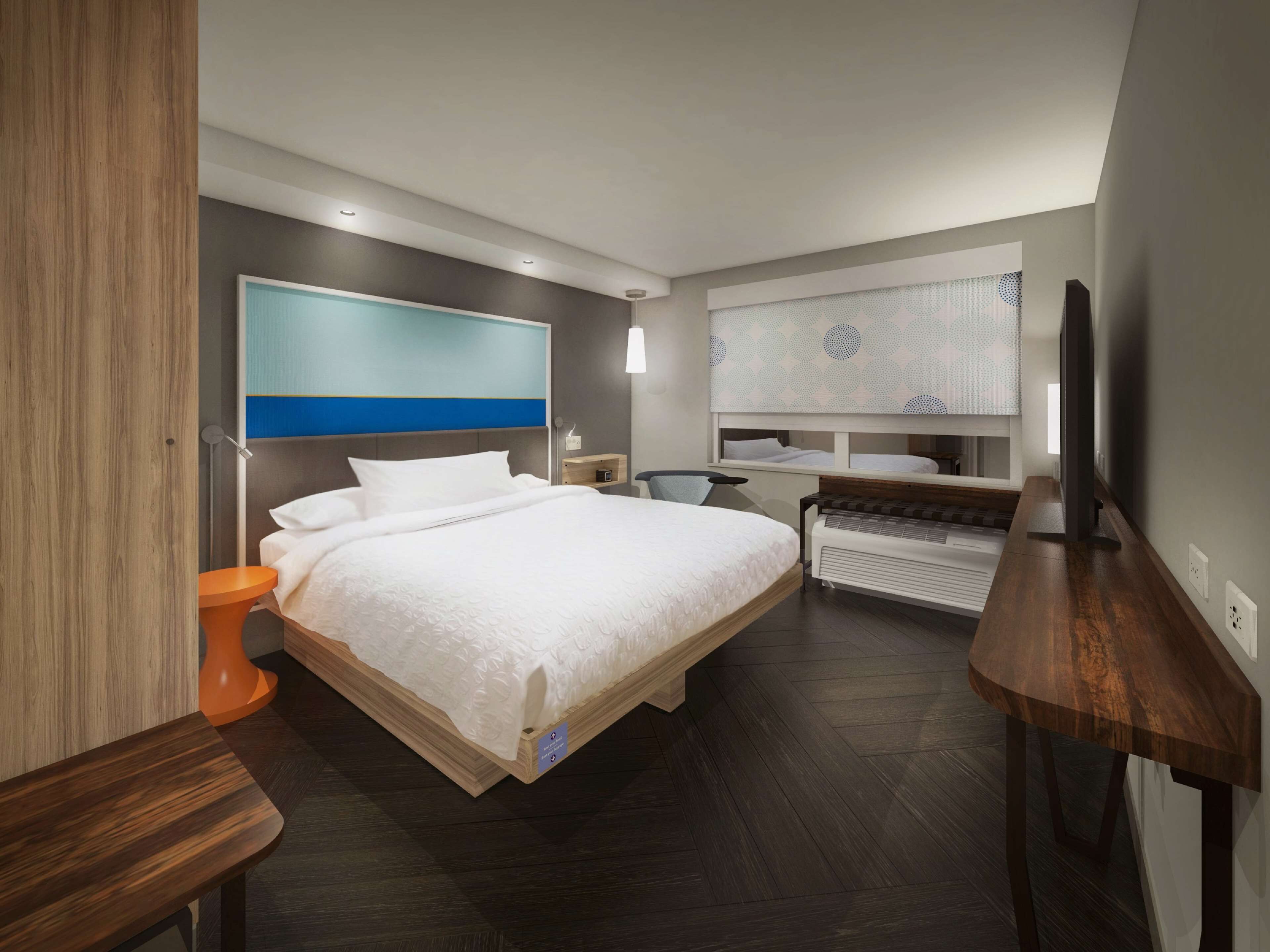 Una habitación de hotel moderna con una cama grande, un escritorio, una silla y un televisor.