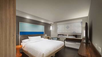 Una habitación de hotel moderna con una cama grande, un escritorio, una silla y un televisor.