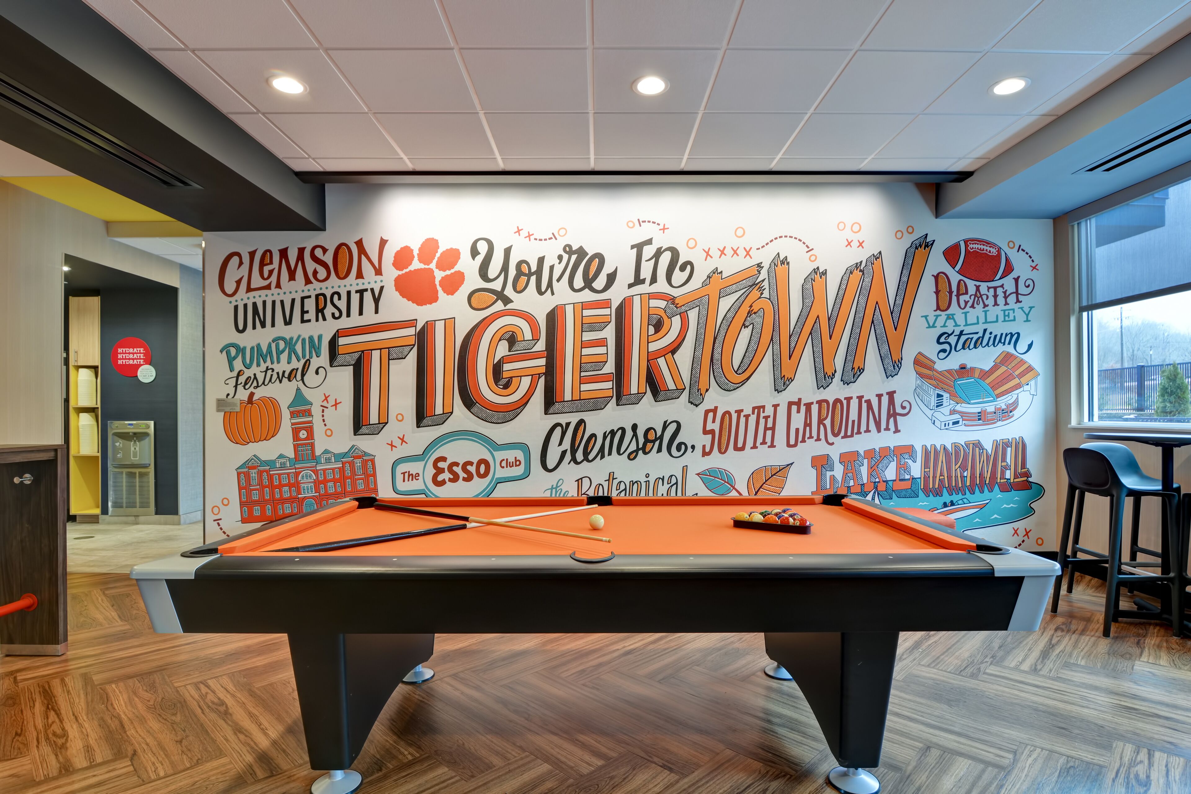 Een pooltafel in een ruimte met een muurschildering van Clemson University en het logo van de Clemson Tigers.