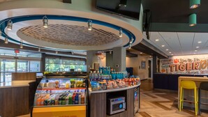 A food court with a beverage display, seating area, and a Clemson University sign. - Tru by Hilton Seneca Clemson (Seneca)