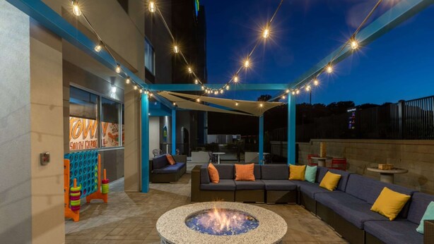 An outdoor patio area with a fire pit, seating, and string lights. - Tru by Hilton Seneca Clemson (Seneca)