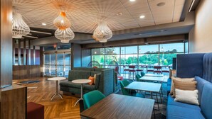 A modern indoor space with a mix of seating options, including a sofa and tables, under stylish pendant lighting. - Tru by Hilton Seneca Clemson (Seneca)