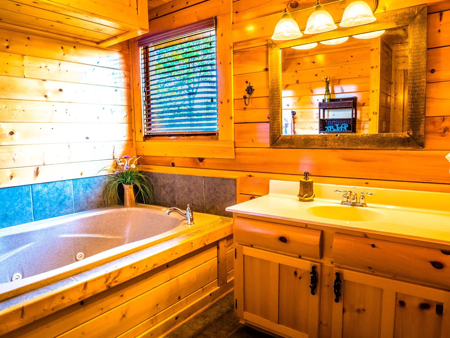 Une salle de bain rustique, aménagée dans une cabane en bois, avec une grande baignoire, un lavabo et un miroir.