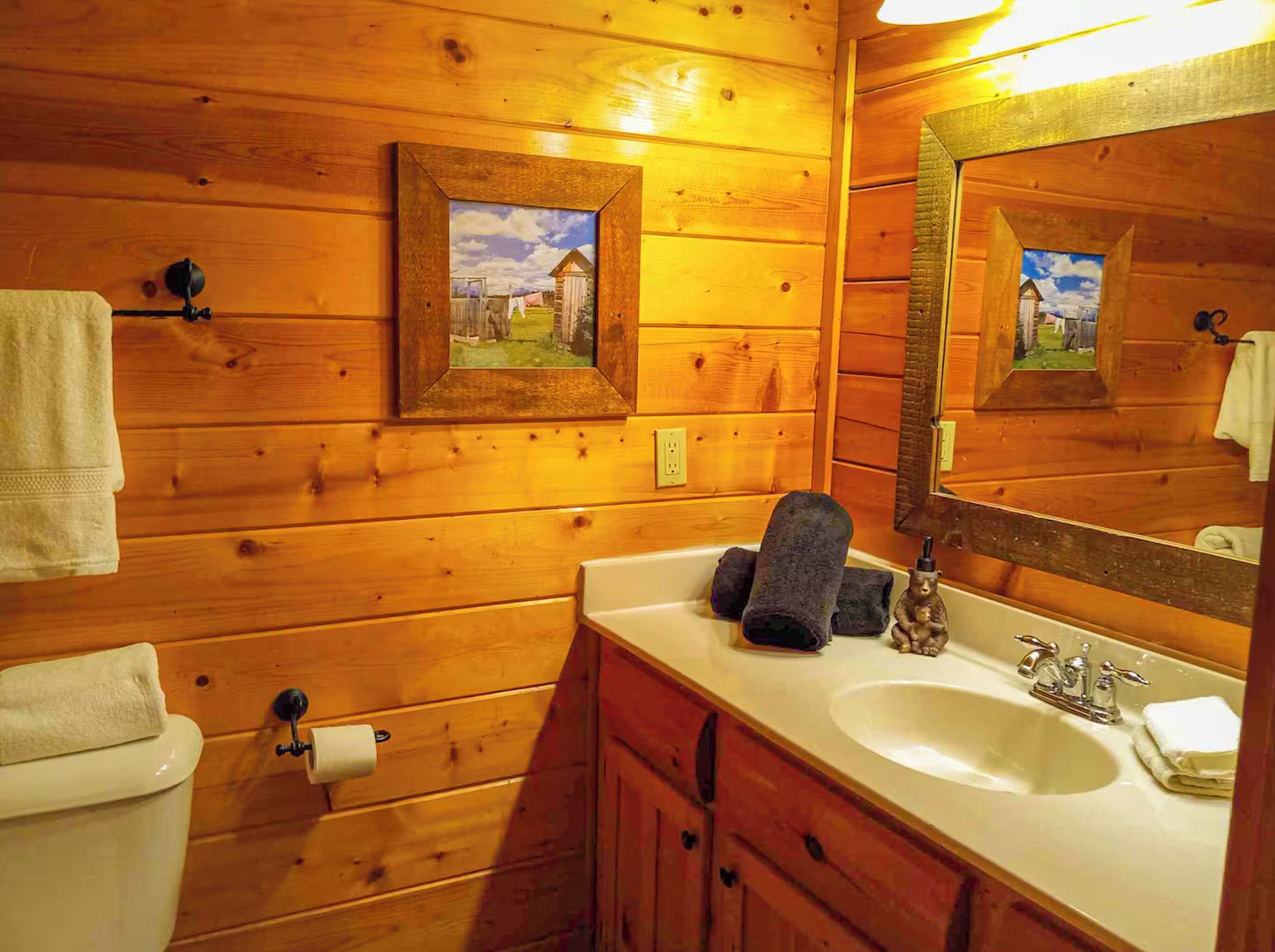 Un bagno in una casetta di legno, con lavandino, specchio e WC.