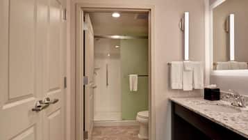 Een moderne badkamer met douche, toilet en wastafel.