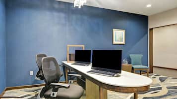 A conference room with two laptops, a wooden table, and two office chairs.