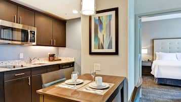 Habitación de hotel con comedor, microondas, lavabo y cama.