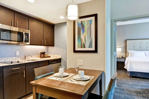 A hotel room with a dining area, a microwave, a sink, and a bed.